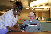 A nurse checks an elderly man's heartrate