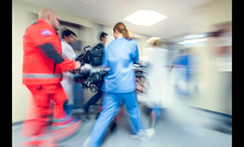 Medical professionals move through a room with a patient on a stretcher