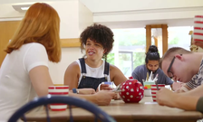 Two women talk to each other while sitting at a table with other residents of a group home