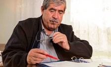 A man sits at a table while reviewing a binder of paperwork