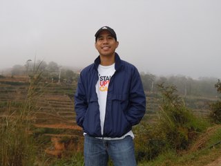 Bautista standing with his hands in his pockets under a cloudy sky at the Banaue Rice Terraces in the Philippines.